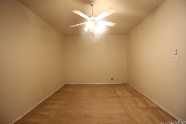 an empty room with a ceiling fan and window