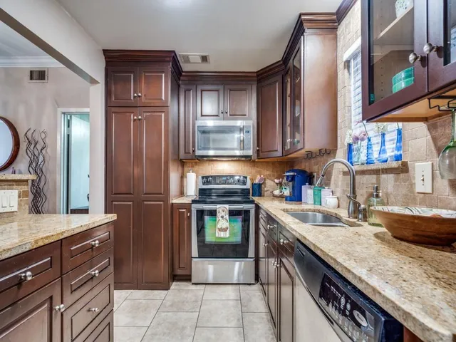 a kitchen with granite countertop a sink stove and refrigerator