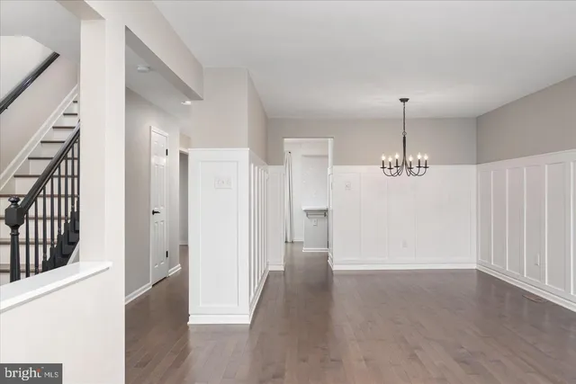 a view of a hallway with wooden floor and chandelier