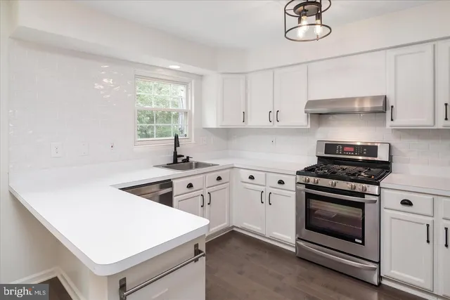 a kitchen with cabinets appliances a sink and a window