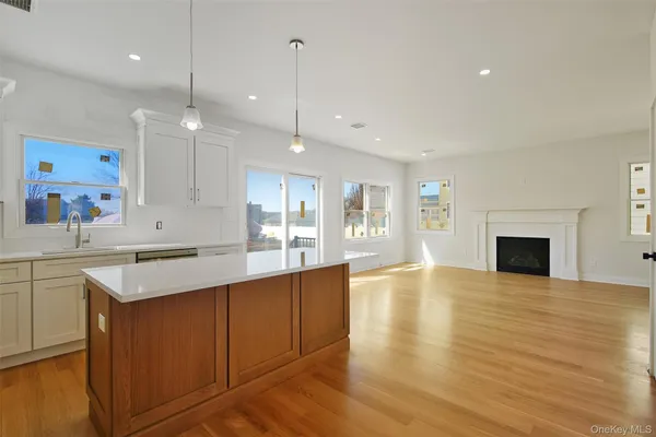 a large kitchen with stainless steel appliances granite countertop a sink a oven and a fireplace with wooden floor