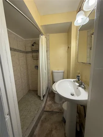 a bathroom with a sink a toilet a mirror and shower
