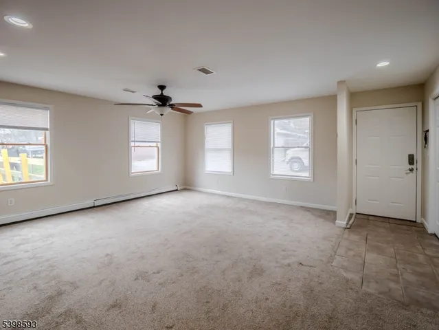 an empty room with windows and ceiling fan