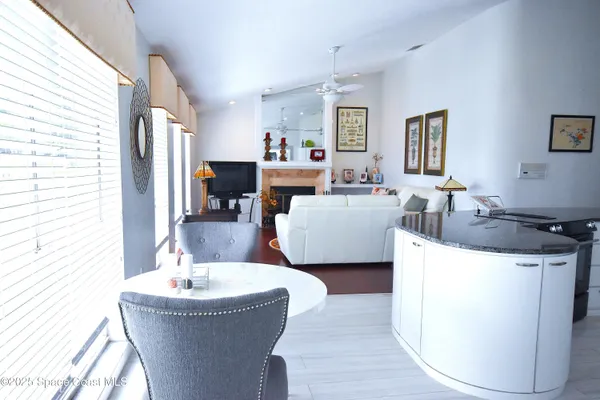 a living room with stainless steel appliances kitchen island granite countertop a sink a kitchen island a fireplace and a large window