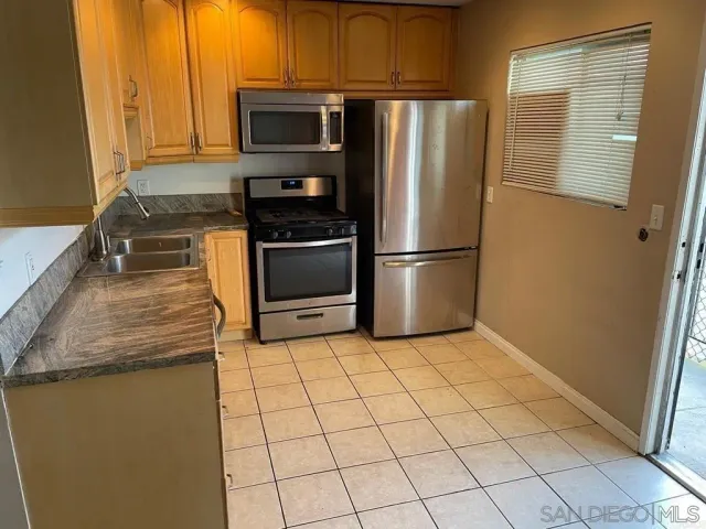 a kitchen with granite countertop a refrigerator and a stove top oven