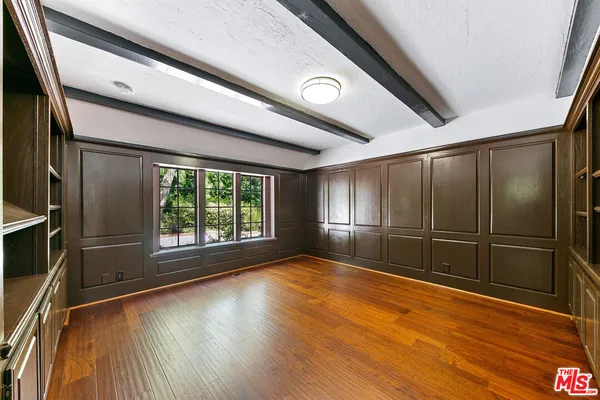 a view of an empty room with wooden floor fireplace and a window