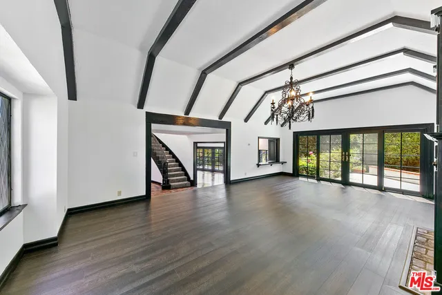 a view of an empty room with wooden floor fireplace and a window