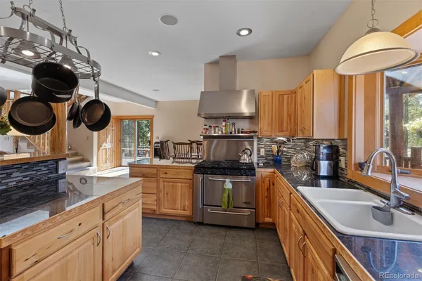 a kitchen with stainless steel appliances granite countertop a sink a stove and a wooden floors