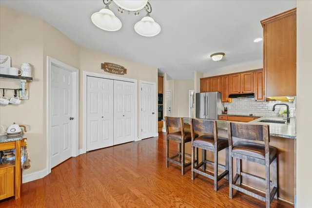 a kitchen with stainless steel appliances a refrigerator a stove a sink a dining table and chairs with wooden floor