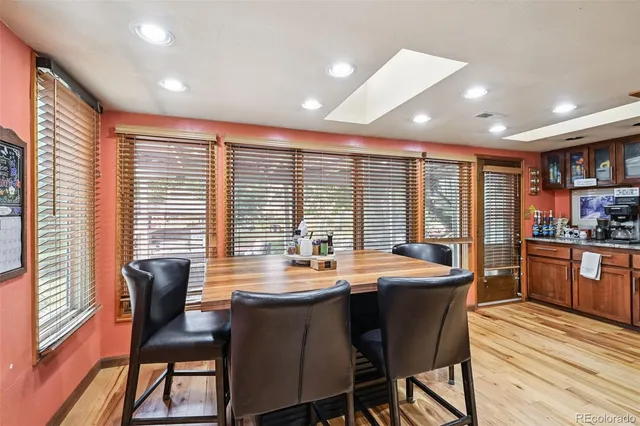 a dining room with stainless steel appliances granite countertop wooden floor a table and chairs