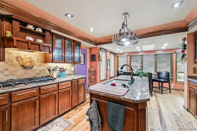 a kitchen with stainless steel appliances granite countertop a stove top oven a dining table and chairs with wooden floor