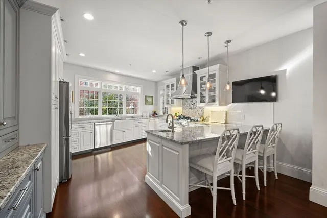 a kitchen with stainless steel appliances granite countertop a stove top oven a sink a dining table and chairs with wooden floor