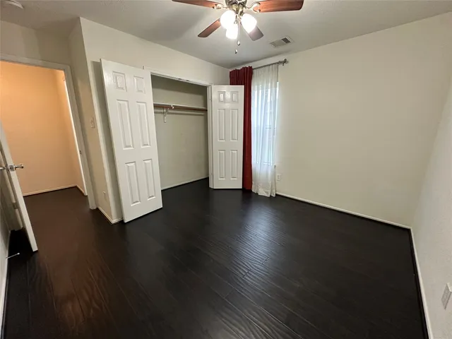 an empty room with wooden floor cabinet and a ceiling fan
