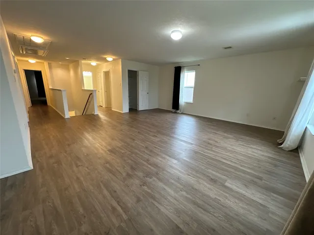 a view of a big room with wooden floor and windows