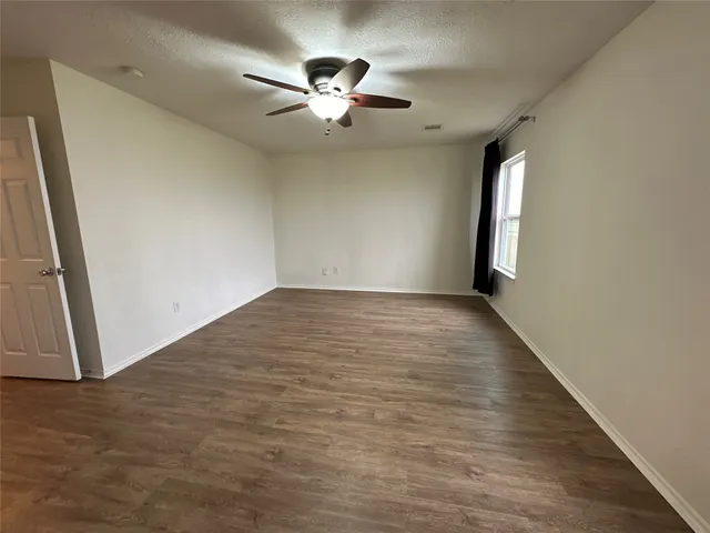 an empty room with wooden floor chandelier fan and windows