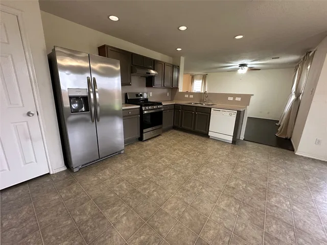 a kitchen with stainless steel appliances granite countertop a refrigerator and a sink