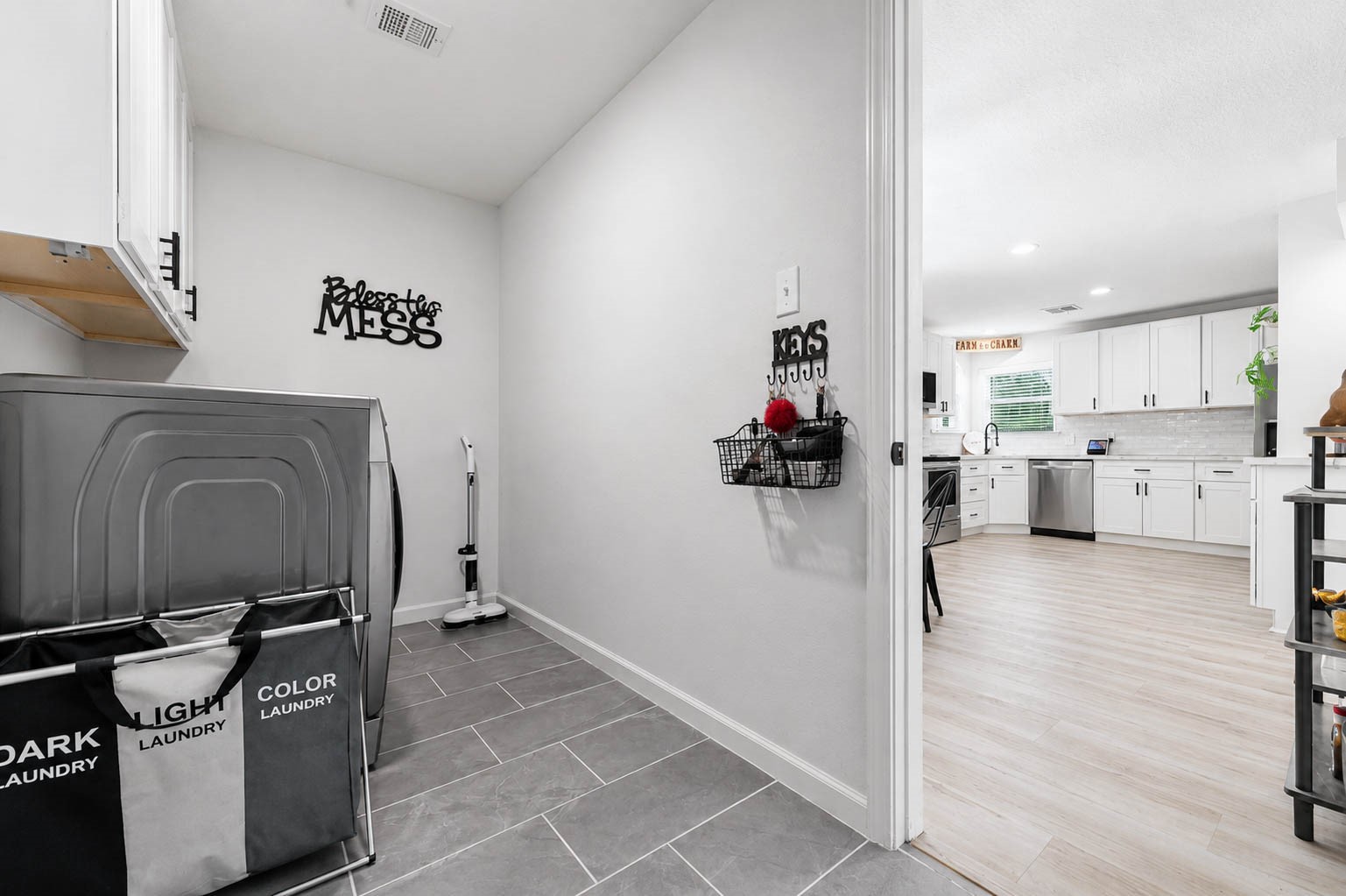 630 South Fry Road Katy, TX 77450 - Photo 19 of 48 A functional laundry area with organized storage leads into a bright, modern kitchen featuring sleek, white cabinetry and stainless steel appliances.