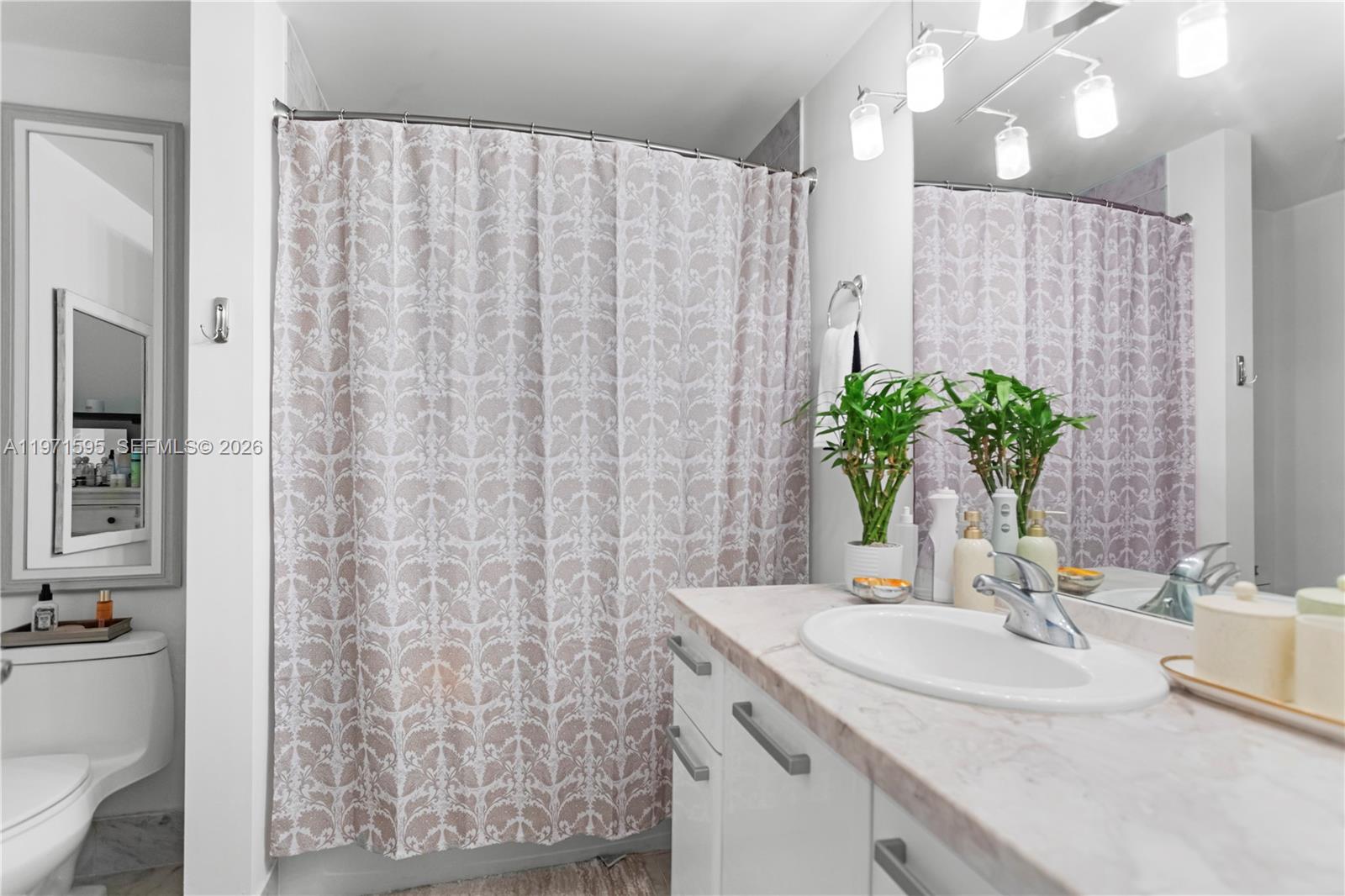 244 Biscayne Boulevard, Unit 252 Miami, FL 33132 - Photo 14 of 18 a bathroom with a granite countertop sink a mirror and a shower curtain