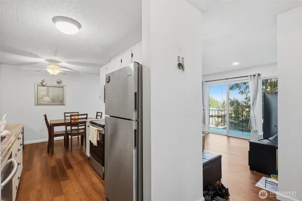 a kitchen with a table chairs refrigerator and wooden floor