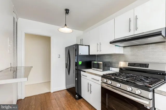 a kitchen with stainless steel appliances a white cabinet and a stove top oven