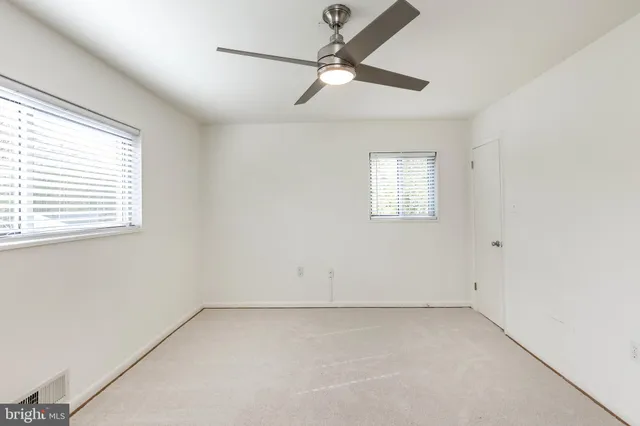 an empty room with a window and a fan