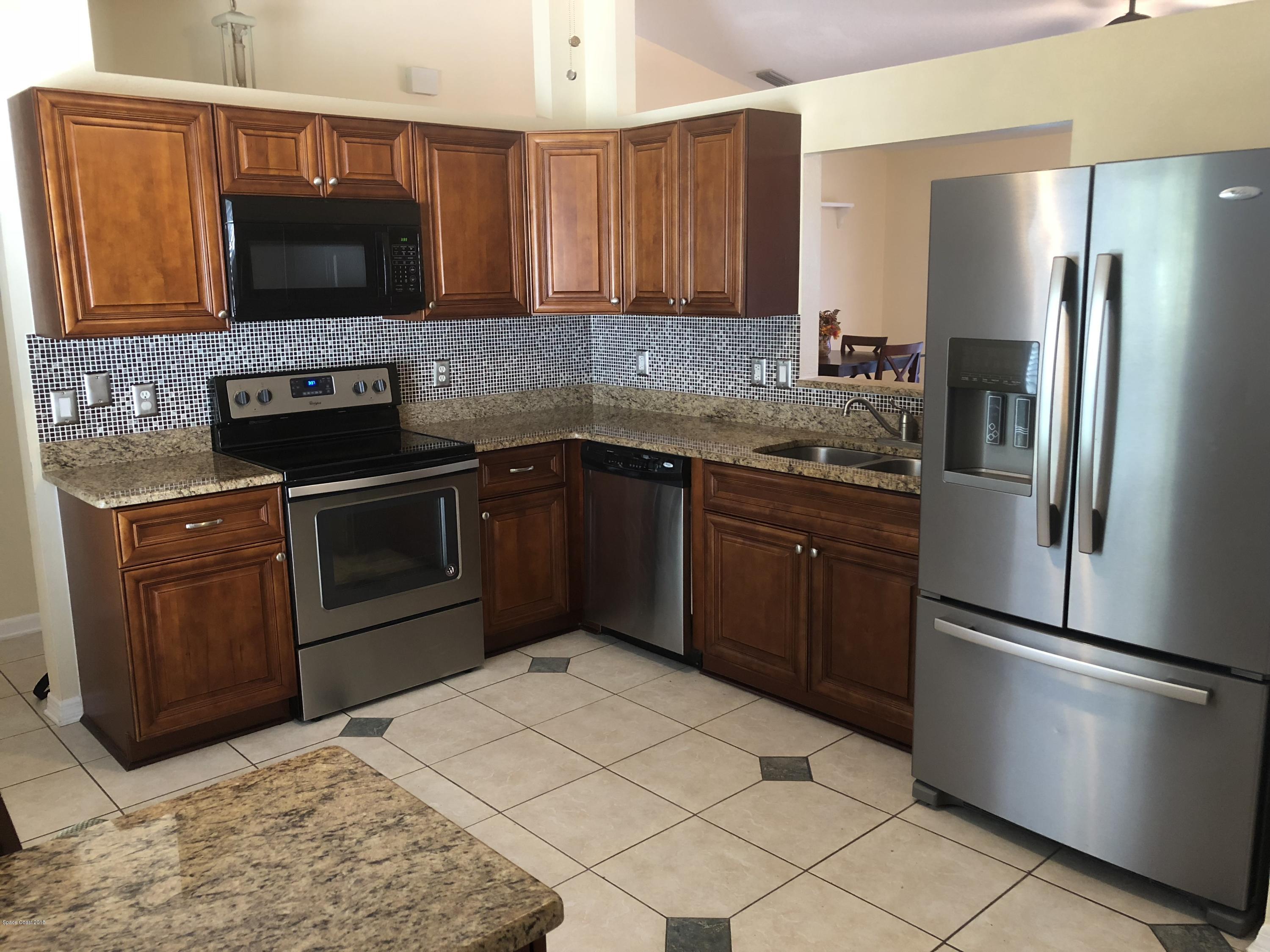 969 Ray Road Southeast Palm Bay, FL 32909 - Photo 3 of 22 a kitchen with stainless steel appliances granite countertop a refrigerator stove and microwave