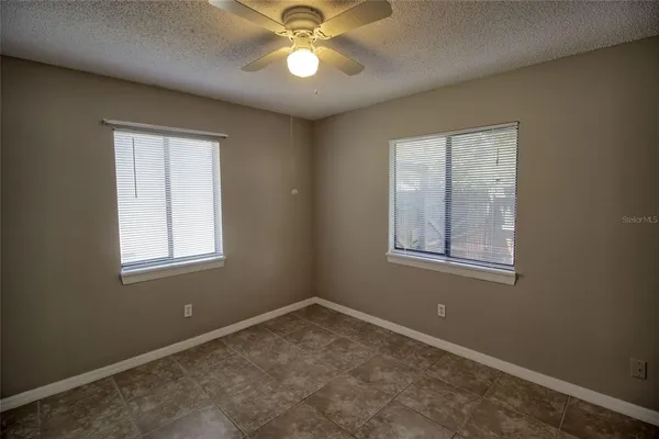 an empty room with windows and fan