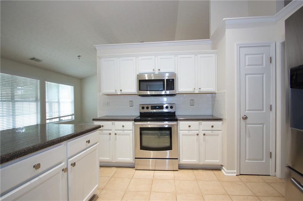 1481 Beckley Pointe Lawrenceville, GA 30043 - Photo 12 of 45 a kitchen with stainless steel appliances granite countertop a stove a sink and a microwave