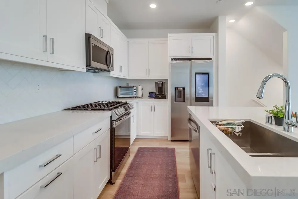 2408 Cascalote Loop San Diego, CA 92154 - Photo 15 of 50 a kitchen with stainless steel appliances granite countertop a sink stove refrigerator and cabinets