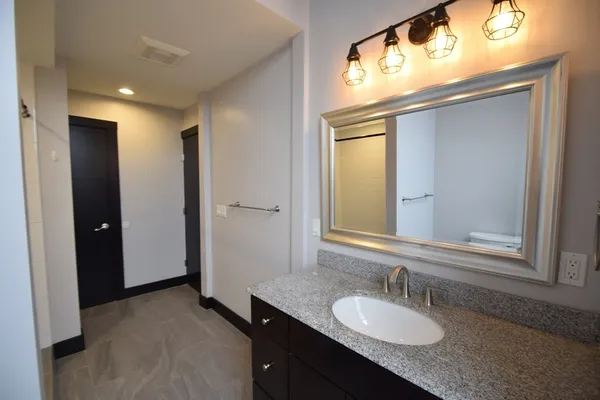a bathroom with a granite countertop sink and a mirror
