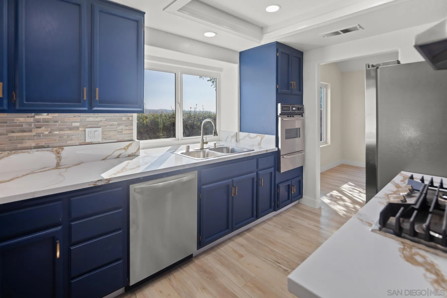10167 Bluestone Court Spring Valley, CA 91977 - Photo 9 of 49 a kitchen with kitchen island granite countertop a sink stainless steel appliances and cabinets