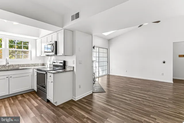 a kitchen with granite countertop stainless steel appliances a sink stove top oven and cabinets
