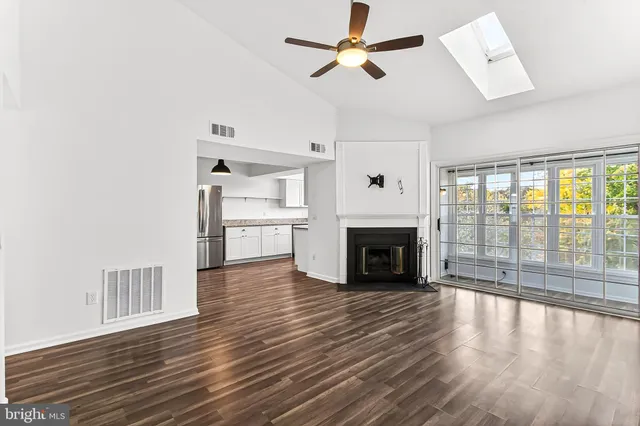 a view of a livingroom with wooden floor a fireplace and windows
