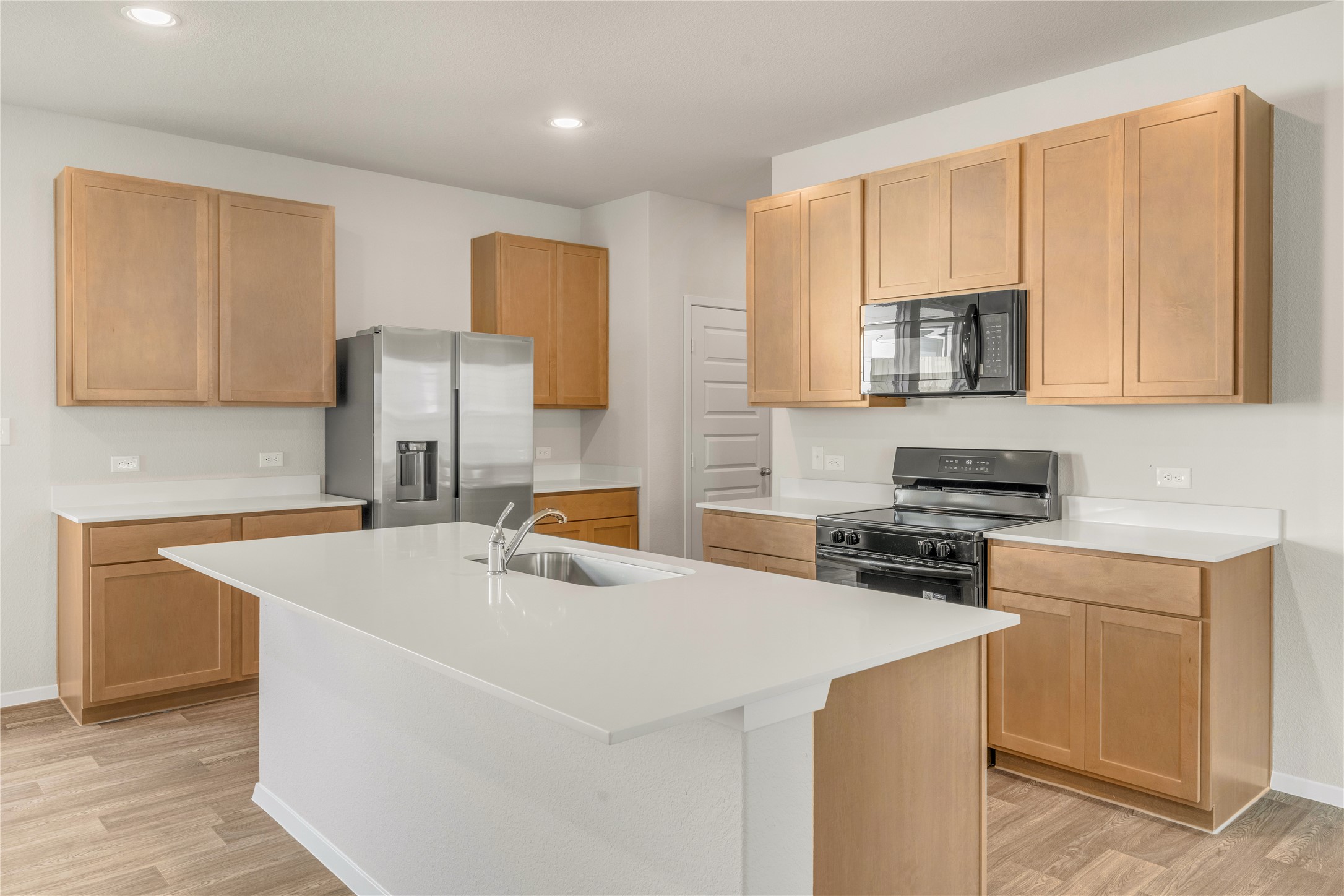 2615 Towy Road Manor, TX 78653 - Photo 10 of 38 Kitchen with electric stove, stainless steel fridge with ice dispenser, a kitchen island with sink, black microwave, and light wood-style floors