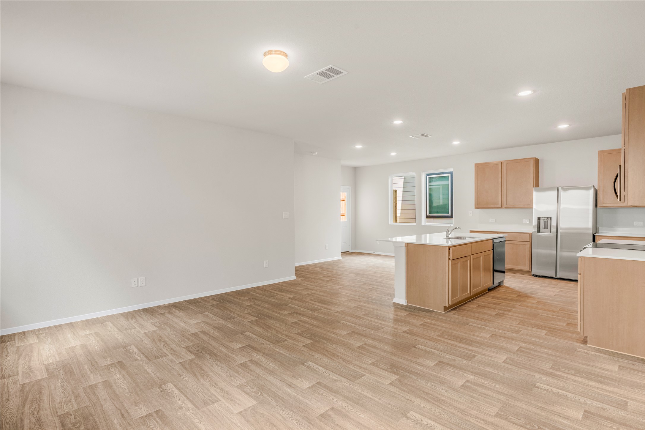 2615 Towy Road Manor, TX 78653 - Photo 36 of 38 Kitchen featuring stainless steel appliances, a kitchen island with sink, light wood finished floors, light wood finish cabinets, and open floor plan