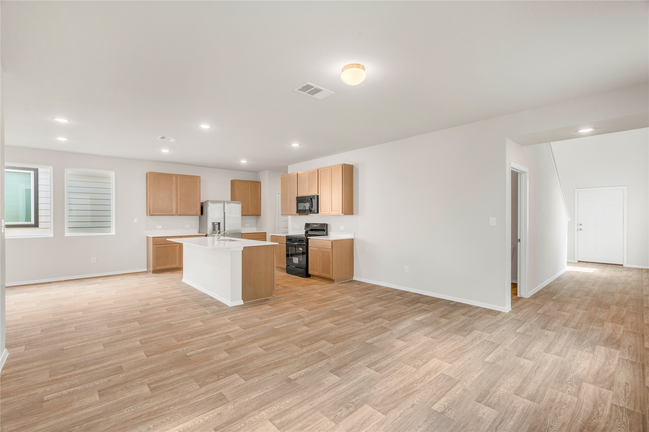 2615 Towy Road Manor, TX 78653 - Photo 37 of 38 Kitchen featuring black appliances, a center island with sink, light wood finished floors, open floor plan, and recessed lighting