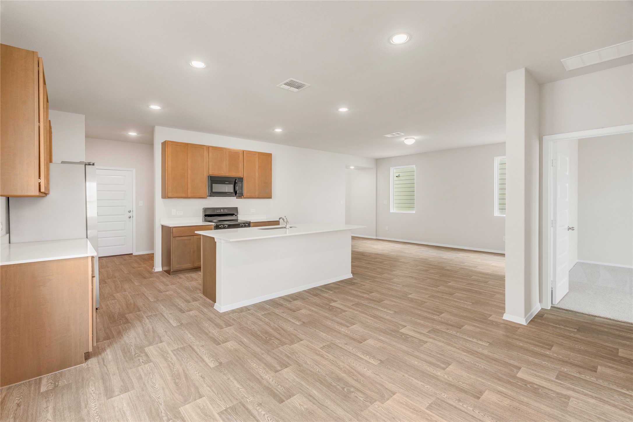 2615 Towy Road Manor, TX 78653 - Photo 6 of 38 Kitchen featuring recessed lighting, black microwave, light wood finished floors, stainless steel range oven, and a center island with sink