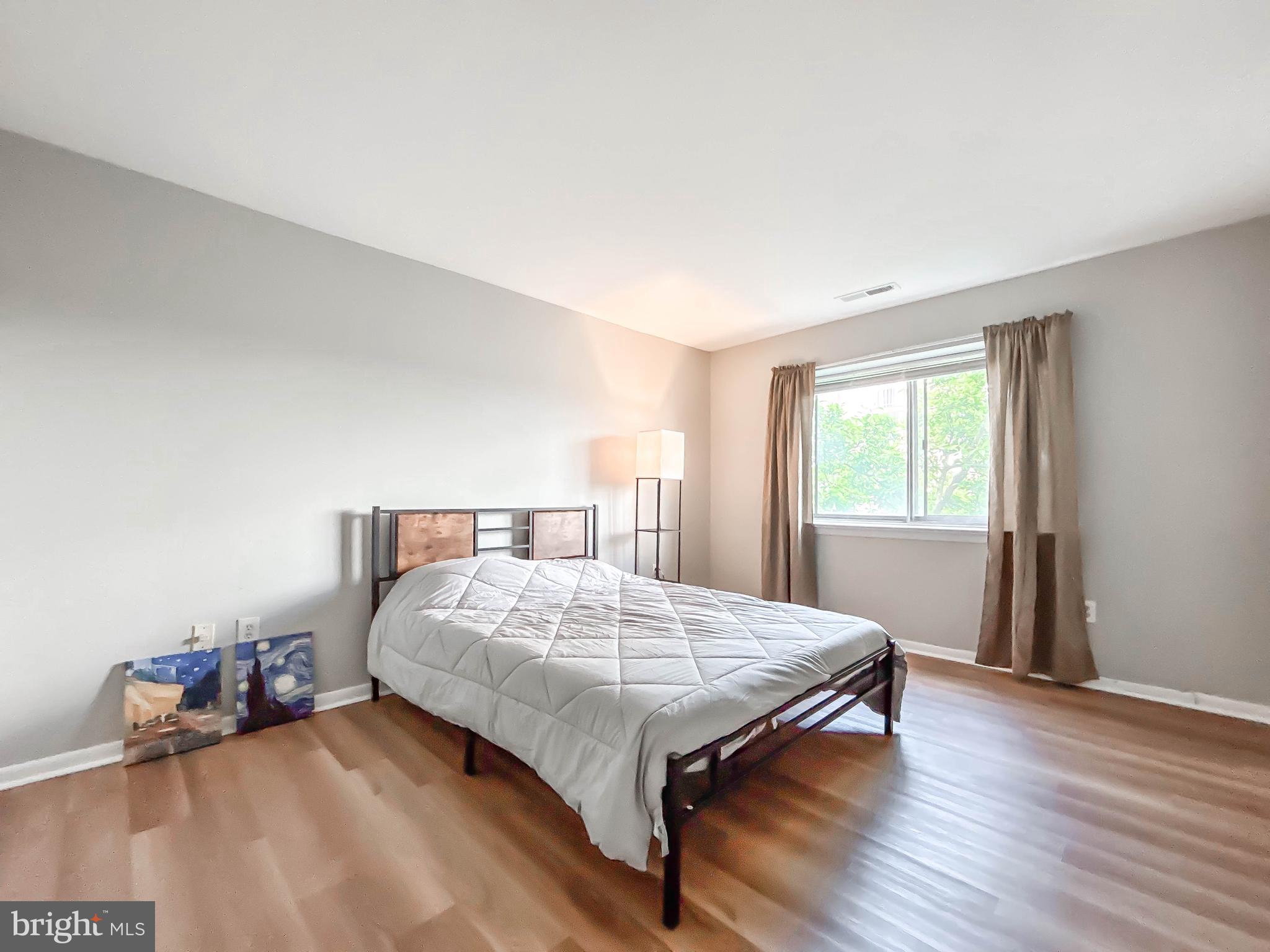 130 Slade Avenue, Unit 414 Baltimore, MD 21208 - Photo 26 of 48 a bedroom with a bed and wooden floor