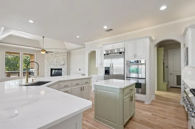 a large white kitchen with a stove a sink dishwasher and a refrigerator with wooden floor