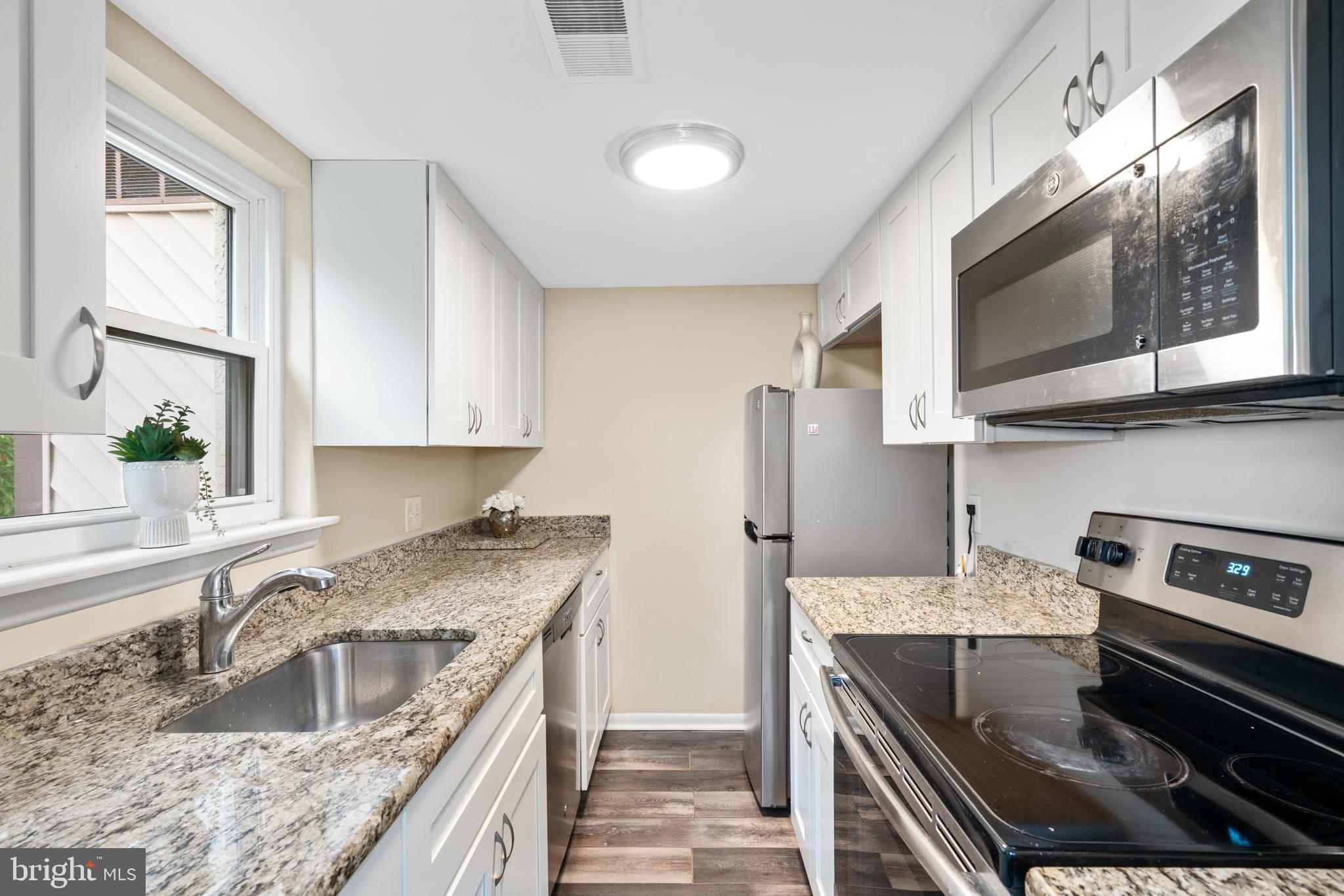233 Township Line Road, Unit 5F Elkins Park, PA 19027 - Photo 7 of 25 a kitchen with stainless steel appliances granite countertop a stove a sink and a microwave