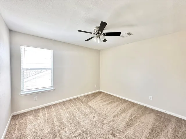 a view of empty room with window and ceiling fan