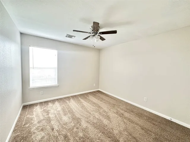 an empty room with a window and a fan