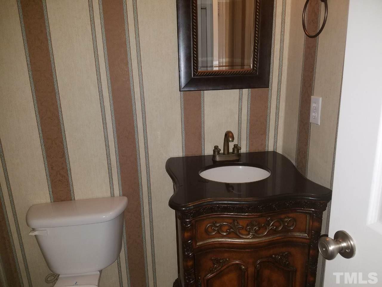 7712 Falcon Rest Circle, Unit 7712 Raleigh, NC 27615 - Photo 8 of 17 a bathroom with a granite countertop sink a toilet and a mirror