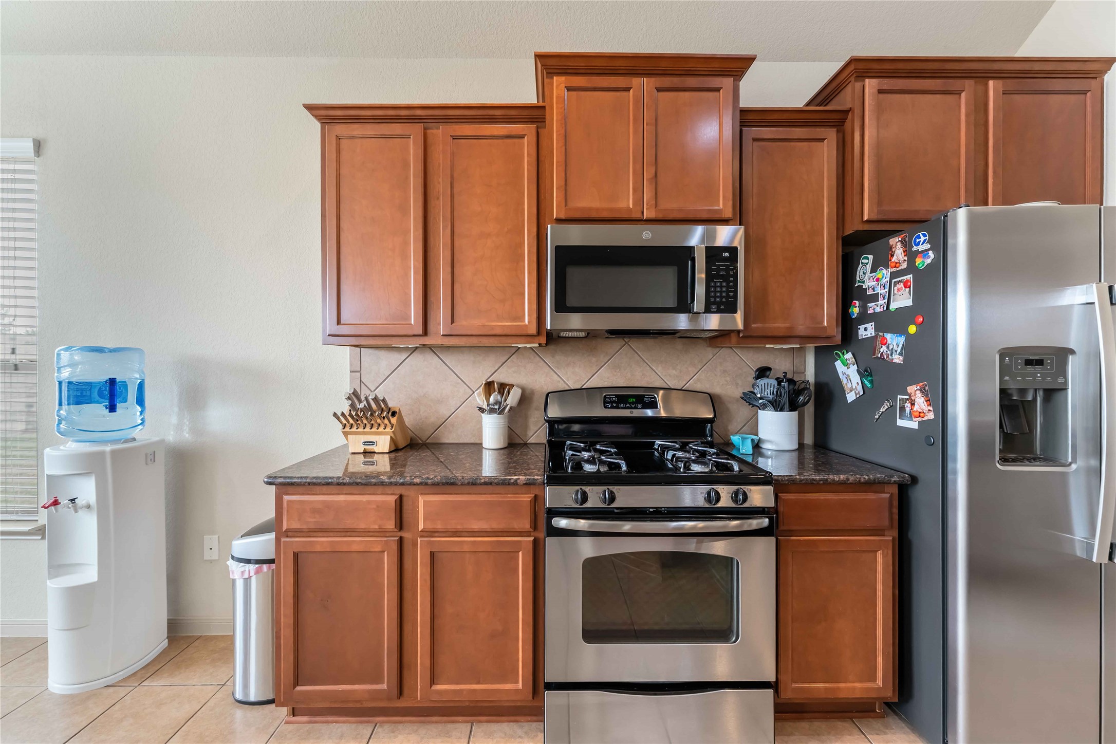2502 Tiger Eye Drive Rosharon, TX 77583 - Photo 23 of 29 This kitchen features sleek stainless steel appliances, and a tiled backsplash. It includes a gas stove, microwave. The space has a modern, functional design.