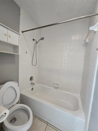 a bathroom with a granite countertop bathtub shower sink vanity and toilet