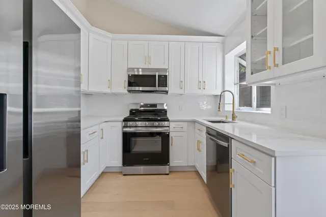 a kitchen with cabinets stainless steel appliances and sink