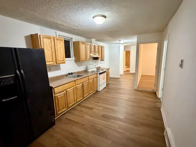 a large kitchen with stainless steel appliances granite countertop a refrigerator a sink dishwasher a stove and white countertops with wooden floor