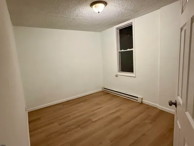 a view of an empty room with wooden floor and windows