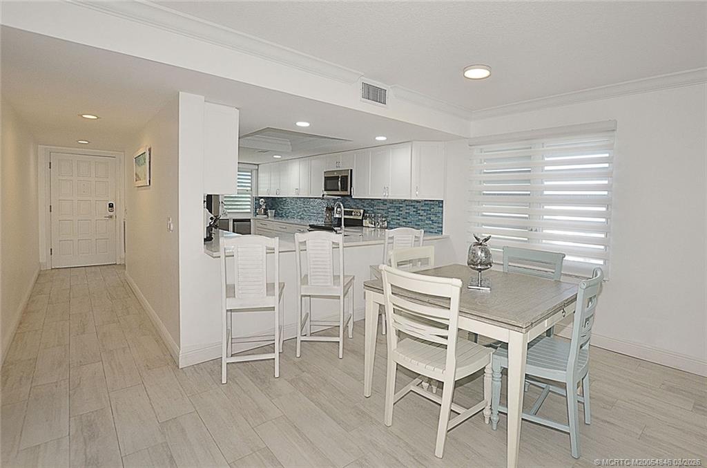 529 Northeast Plantation Road, Unit 310 Jensen Beach, FL 34957 - Photo 7 of 12 a kitchen with stainless steel appliances kitchen island granite countertop a table chairs sink and cabinets