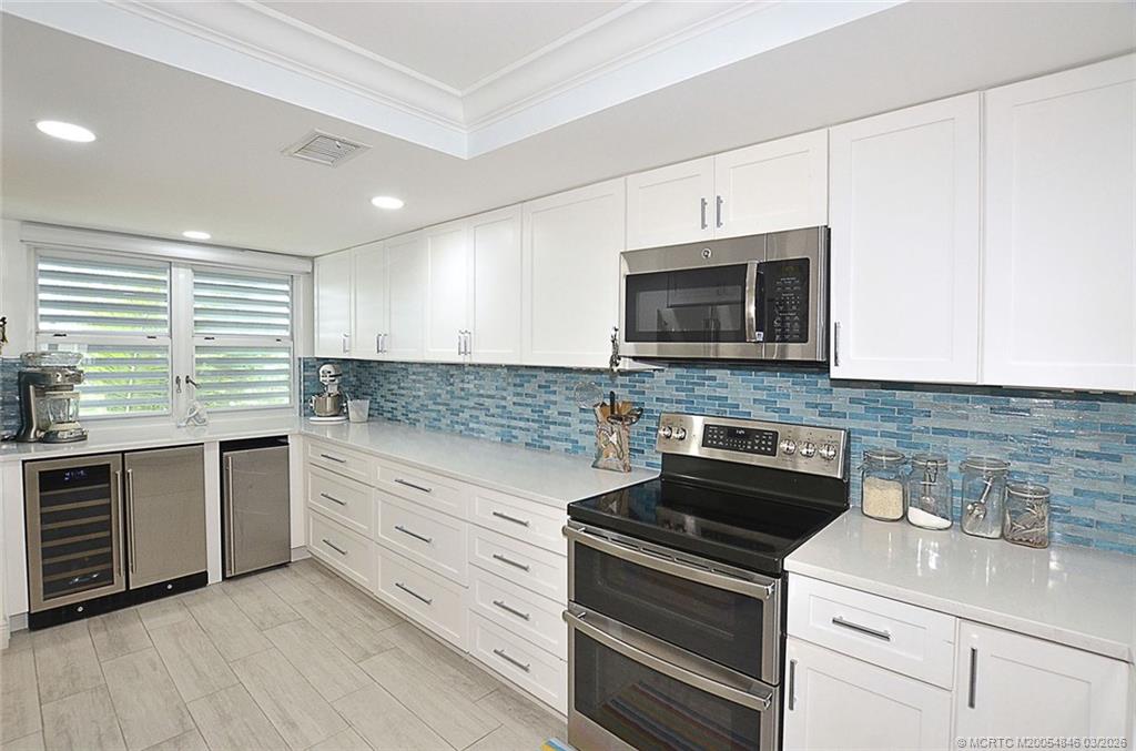 529 Northeast Plantation Road, Unit 310 Jensen Beach, FL 34957 - Photo 9 of 12 a kitchen with granite countertop white cabinets and appliances